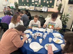 Students decorating cookies around a table with snacks in a vibrant classroom.