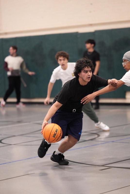 A player dribbles the ball while others chase during a game.