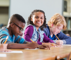 Three diverse students taking a test with the middle child smiling at the camera