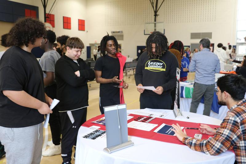 group of students listen to a person talking about resources at a table
