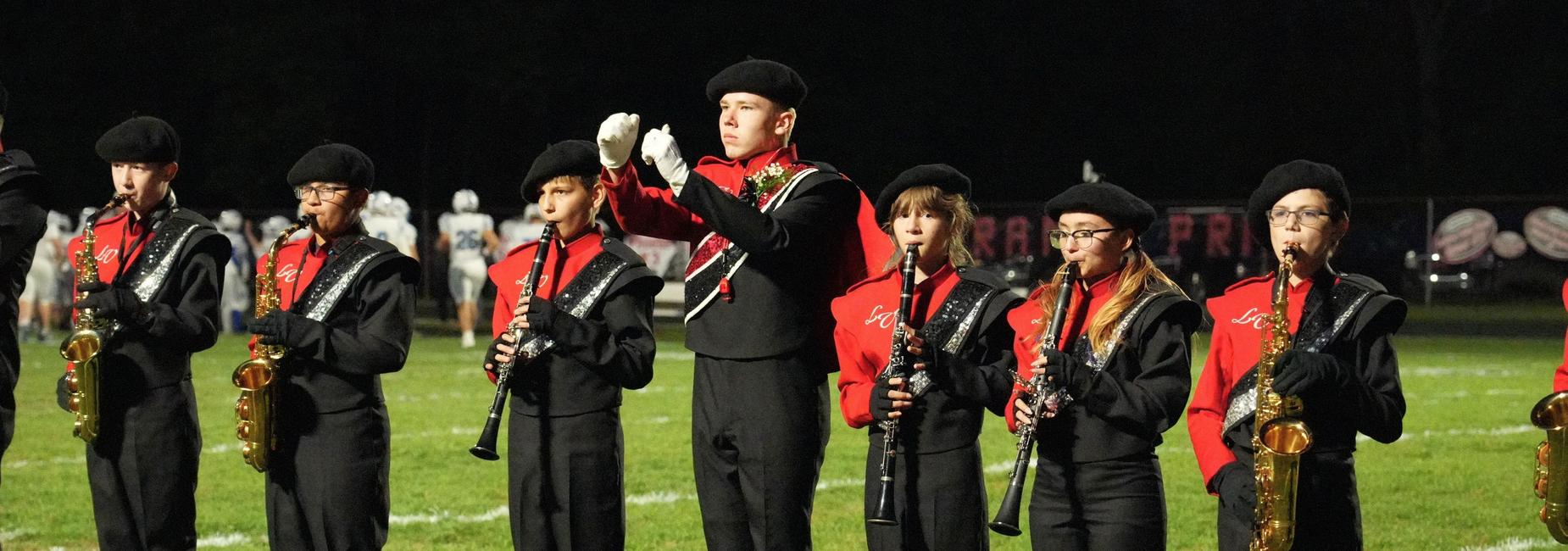 A marching band playing instruments during a nighttime event.