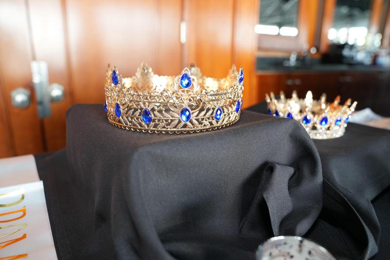 Two elegant crowns with blue gems on a black cloth.