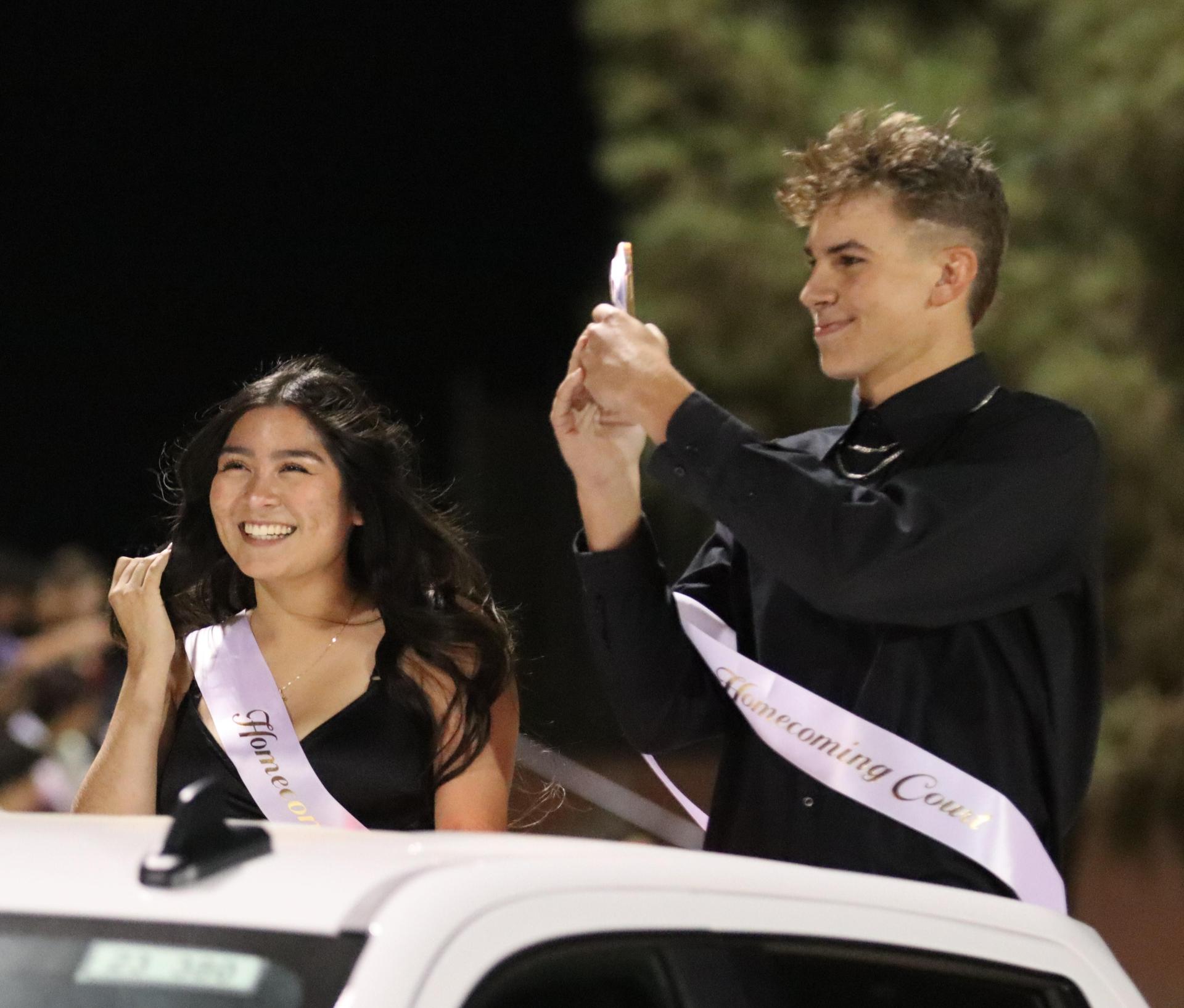 homecoming king and queen candidates entering the stadium in trucks