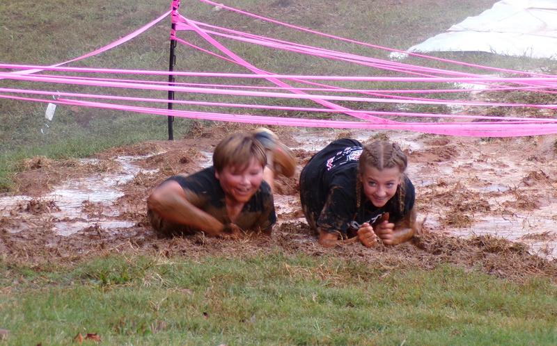 Two students navigate the mud pit at the Rebel Challenge