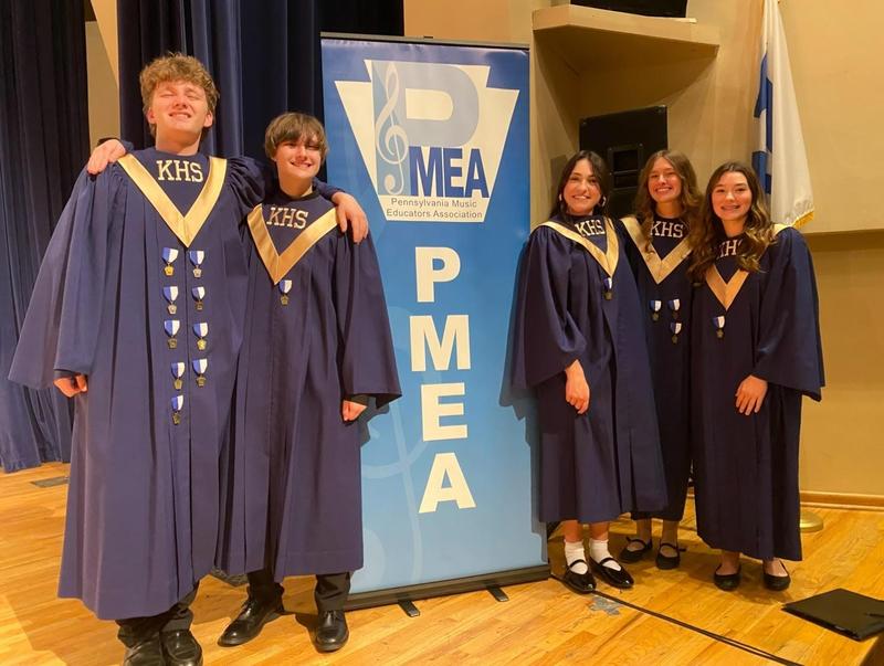 students dressed in navy chorus robes in front of pmea sign