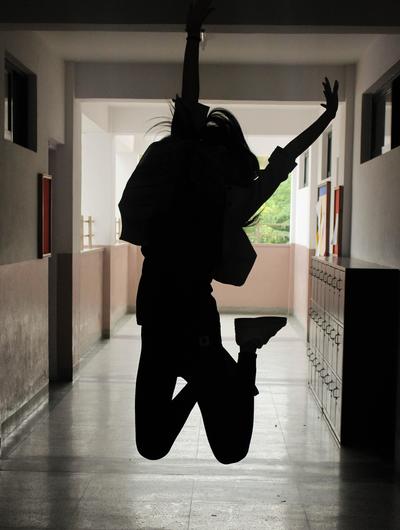 A silhouette of a person jumping in a hallway, arms raised.