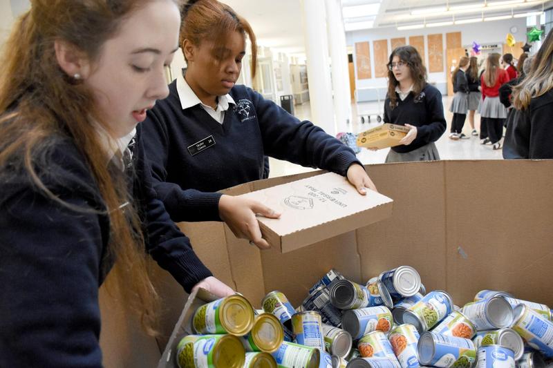 Students organize canned goods in a large box for a food drive.