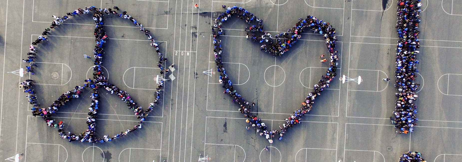 Aerial view of people forming a peace sign and heart on a basketball court.