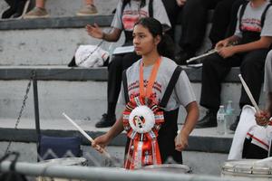 Drummer wearing a gray shirt with a large orange and black ribbon.