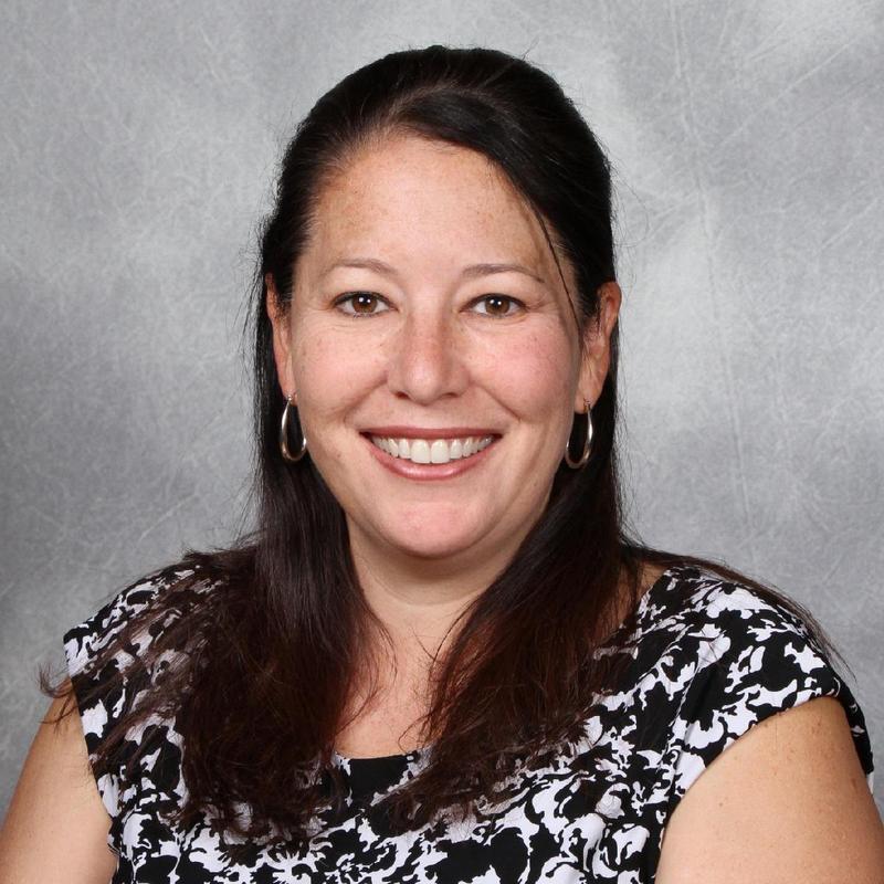 Jennifer Ambrose, a woman with shoulder length brown hair in a black and white floral blouse smiling