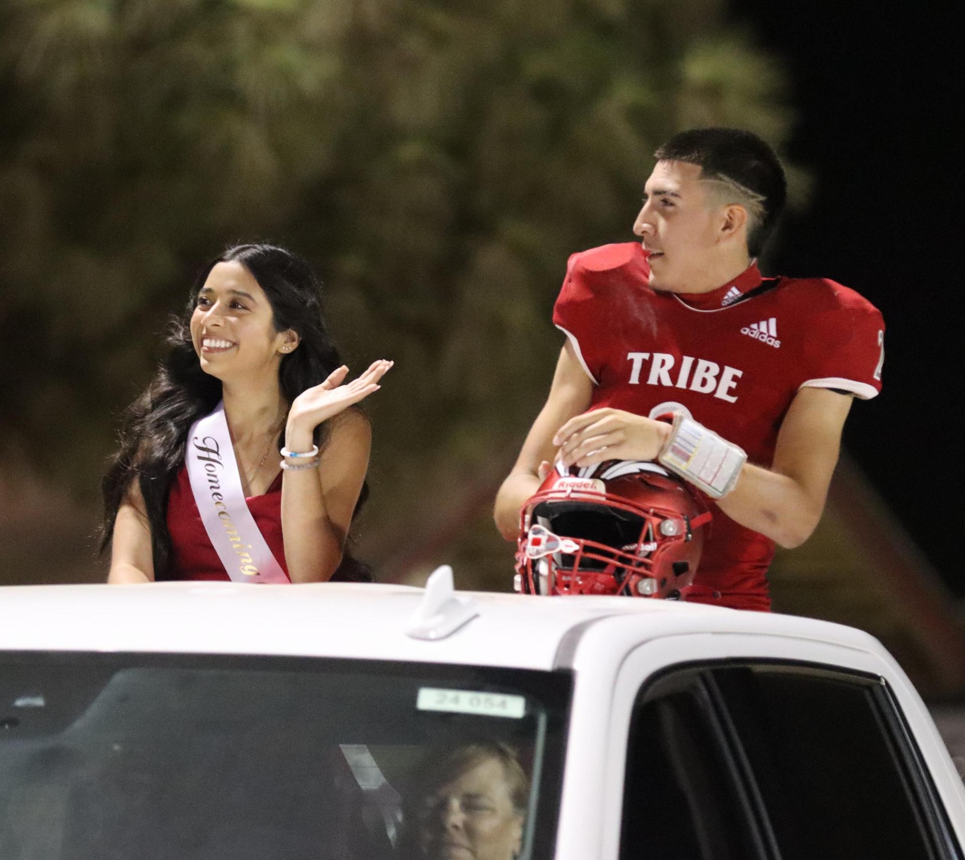 homecoming king and queen candidates entering the stadium in trucks