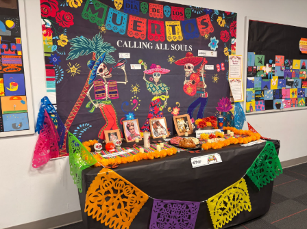 A colorful ofrenda with items labeled in English and Spanish
