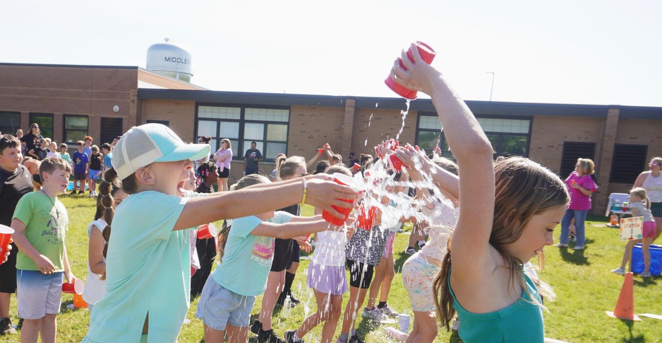 Children participate in a water splashing activity outdoors.