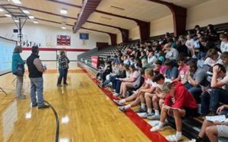 Graduates in red gowns joyfully tossing their caps into the air during a celebration.