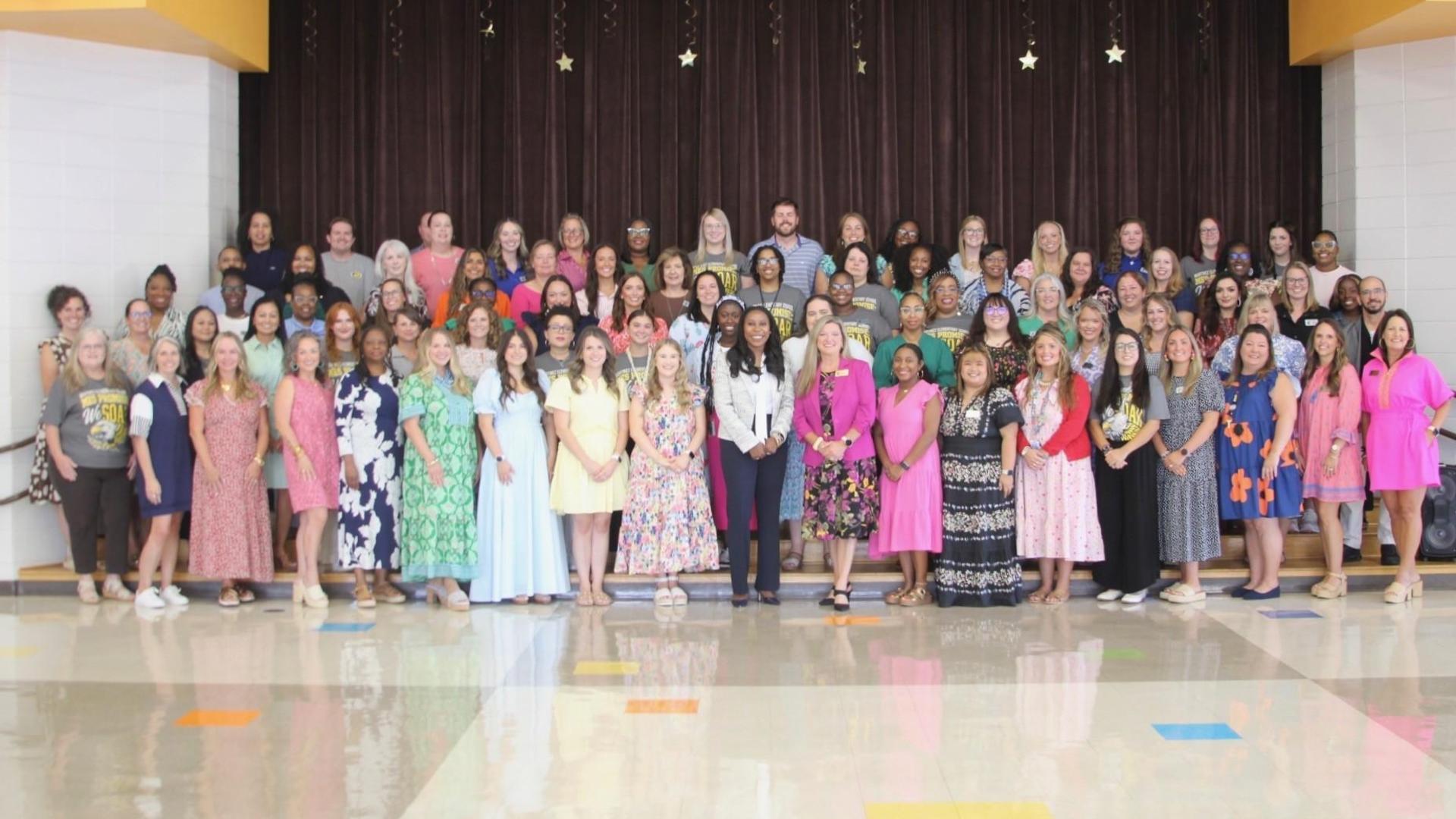 Large group of diverse people posing together, dressed in colorful attire.