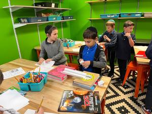 two third grade students roll tubes to keep their bridge suspended.