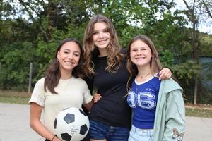 Three girls, outside, smile at camera
