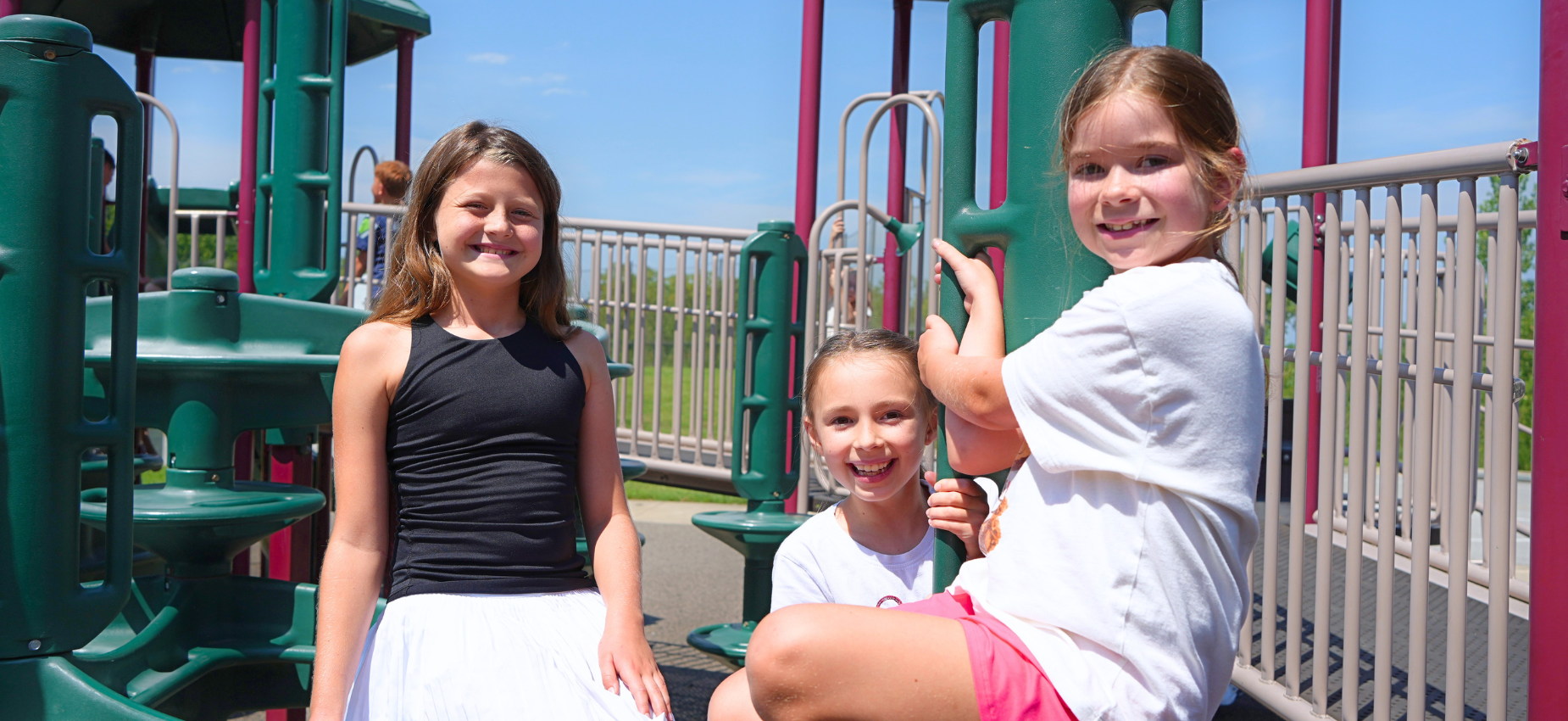 Three girls posing on a playground structure.