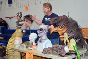 Man showcasing various detailed monster sculptures at a display.