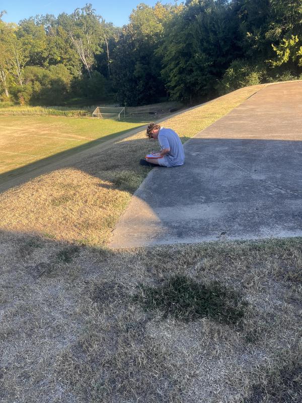 a student sitting on the concrete, writing