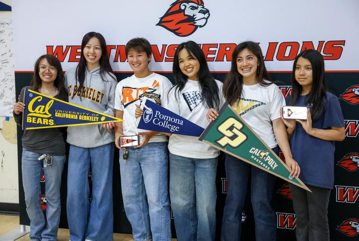 students standing with different college flags on decision day