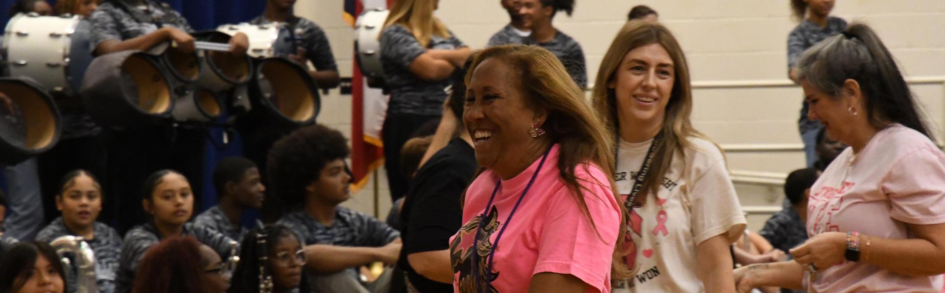 A joyful celebration in a school with participants smiling and performing on stage.