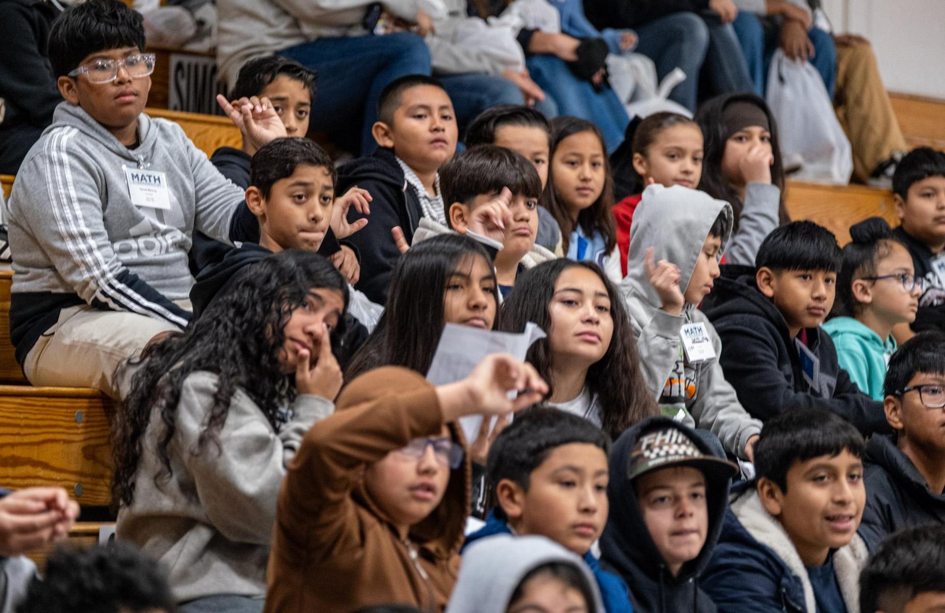about 19 students sitting on gym bleachers
