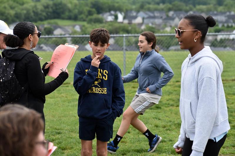 Children engaging in activities on a grassy field with adults supervising.