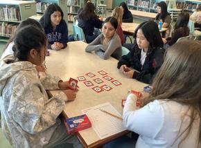a group of students sit at a table playing an educational memory card game