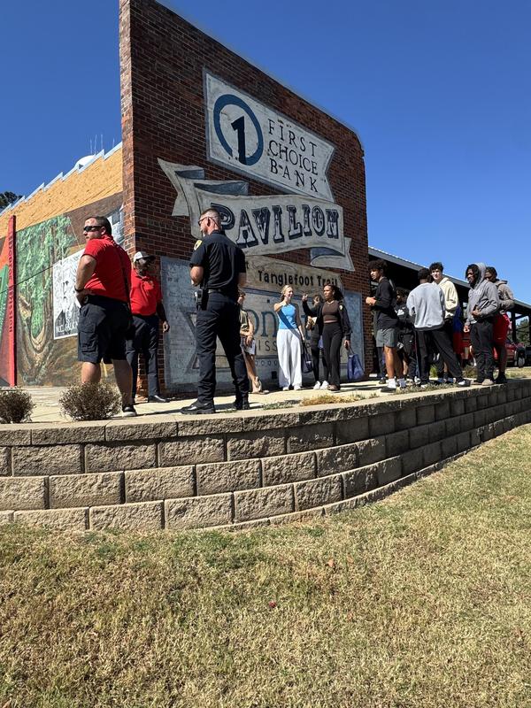Students and adults in front of pavilion mural