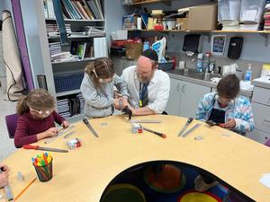 Third grade girls sanding down their medal rods for their menorah