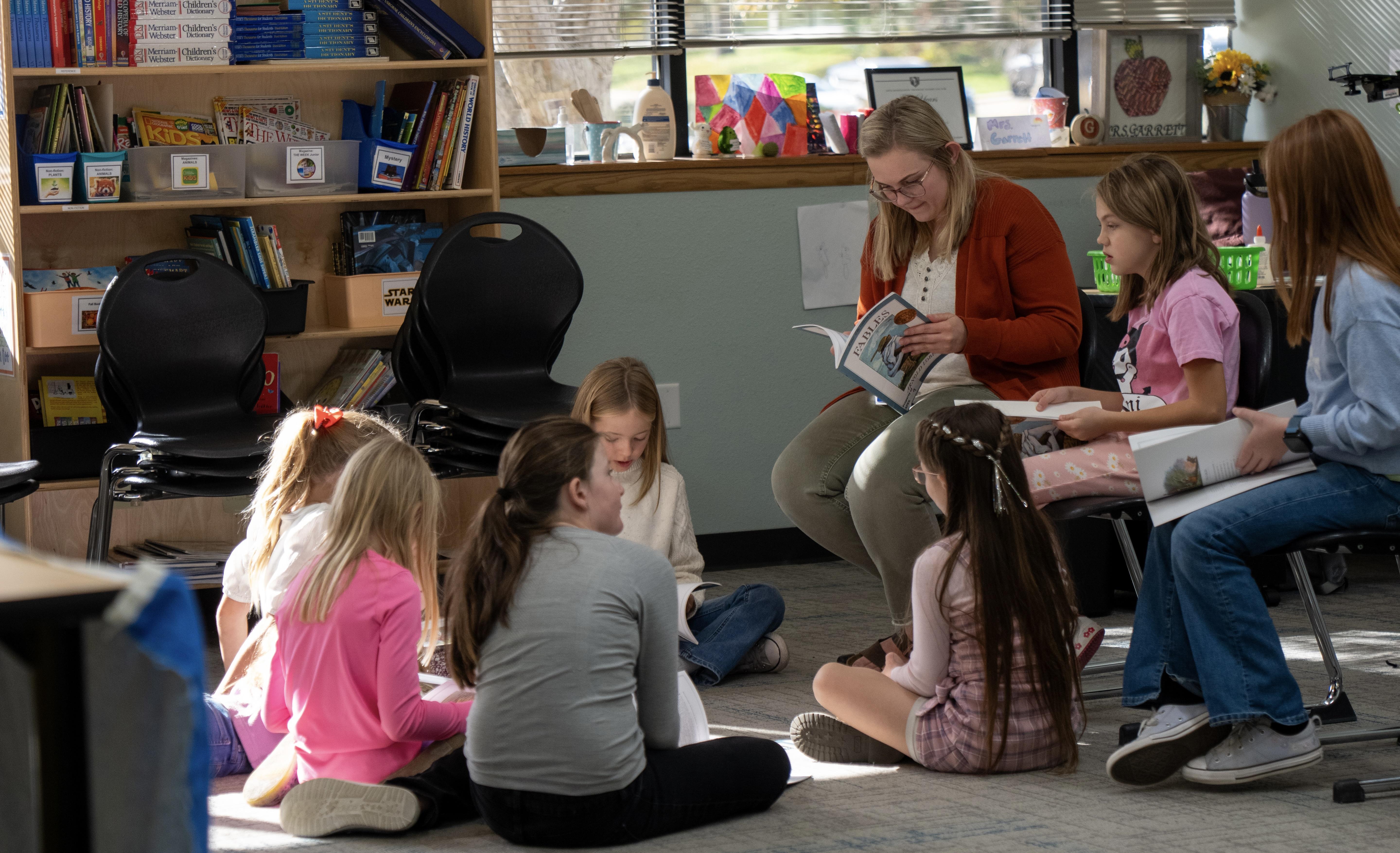 students sitting on the floor gathered around their teacher
