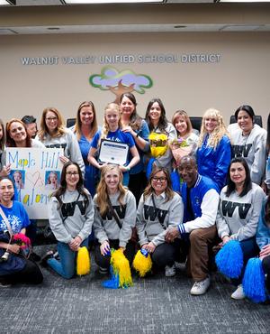 Group photo of women holding a certificate and pom-poms at a school event.