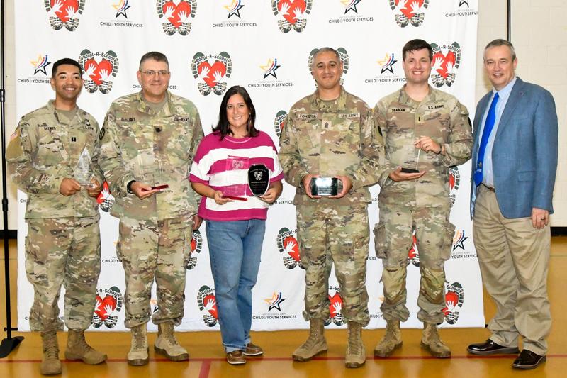 A group of people smiling and holding awards in front of a backdrop