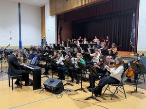 large group of students holding band or orchestra instruments on stage