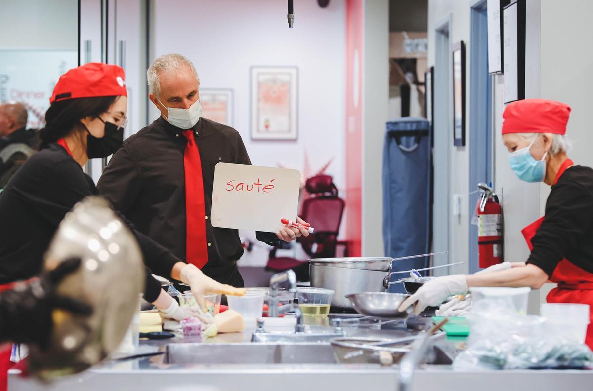 two culinary students and their instructor with cooking tools and a sign that says sautee