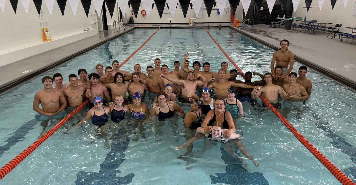 Members of the football team and swim team engage in a friendly competition in the pool.