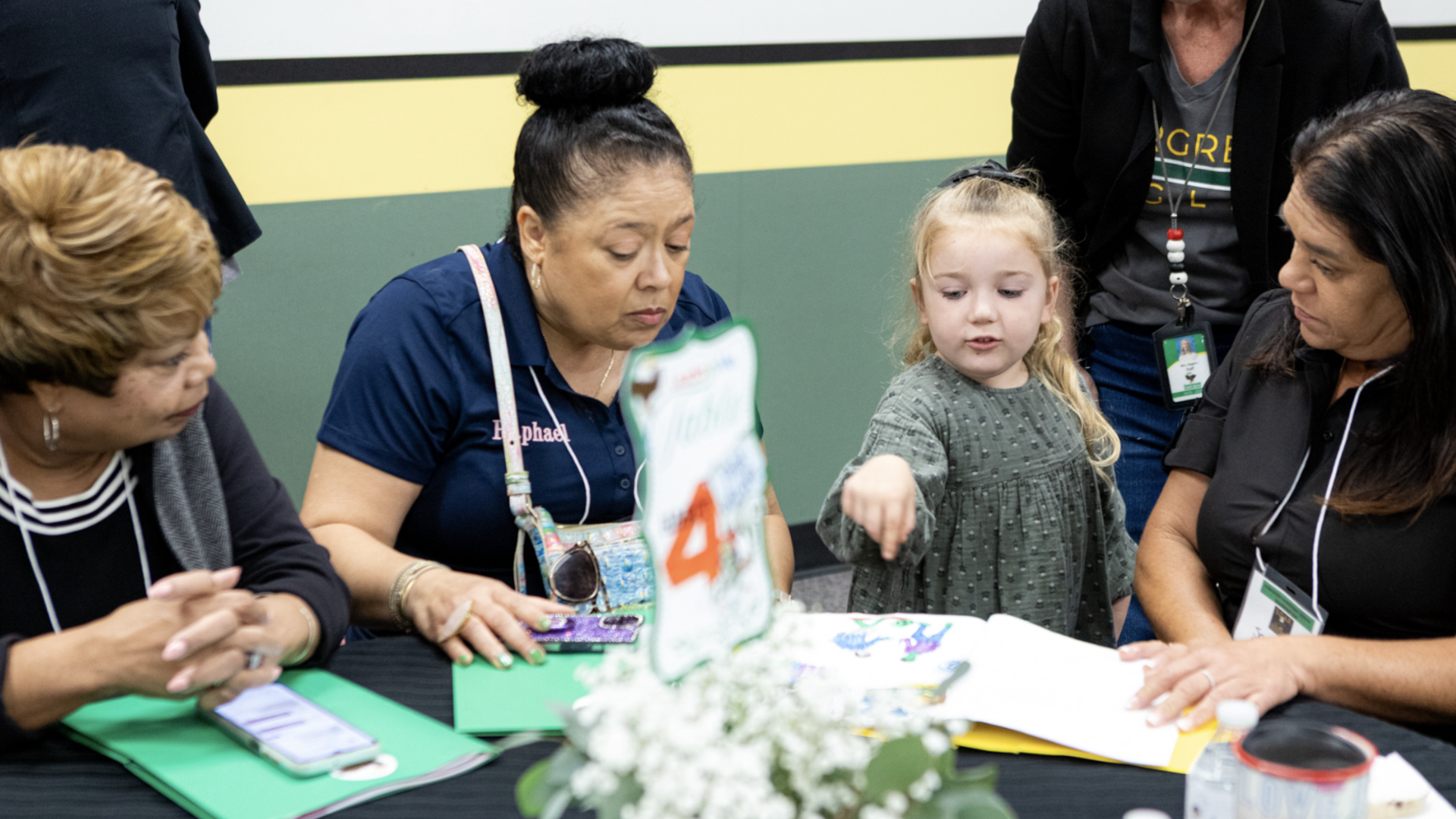 A group of four women and a young girl engaged in discussion at a table.