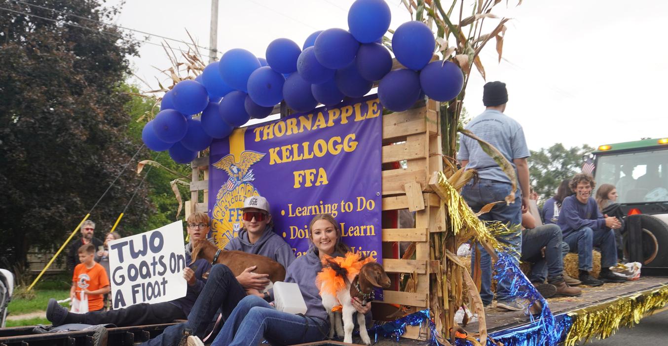 TK FFA students sit on the homecoming float holding two baby goats.