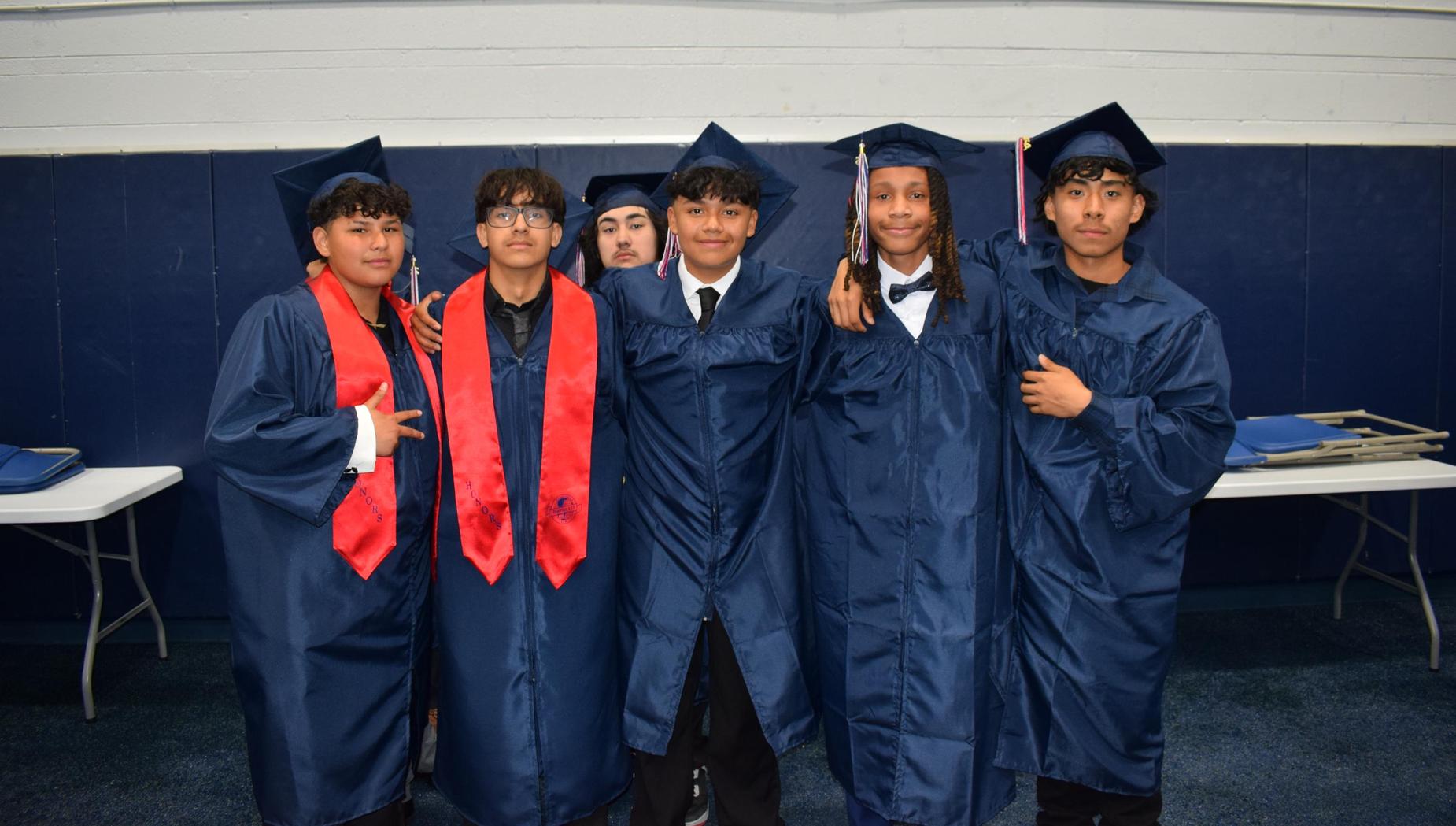 A group of graduates in caps and gowns posing together for a photo.