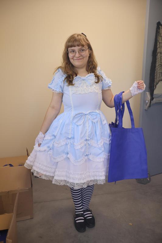 Student volunteer Haley greets visitors to Trek@Tech in blue and white dress