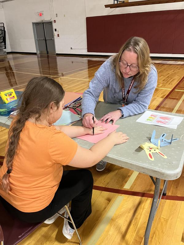 Adult assisting a child with art activities at a table.