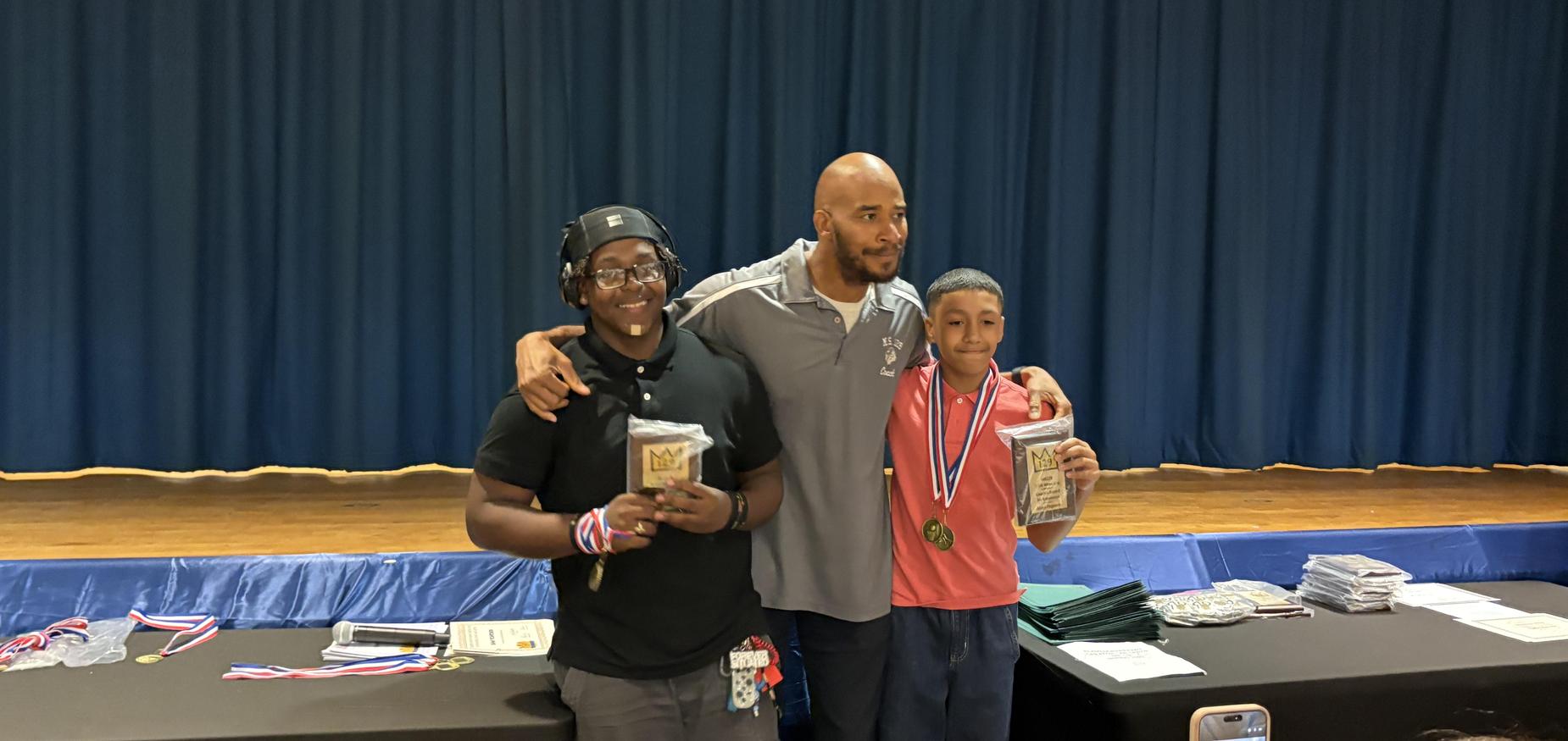 Wrestling coach standing between two students