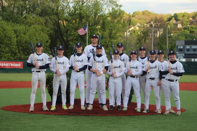 12 boys dressed in baseball uniforms holding bats