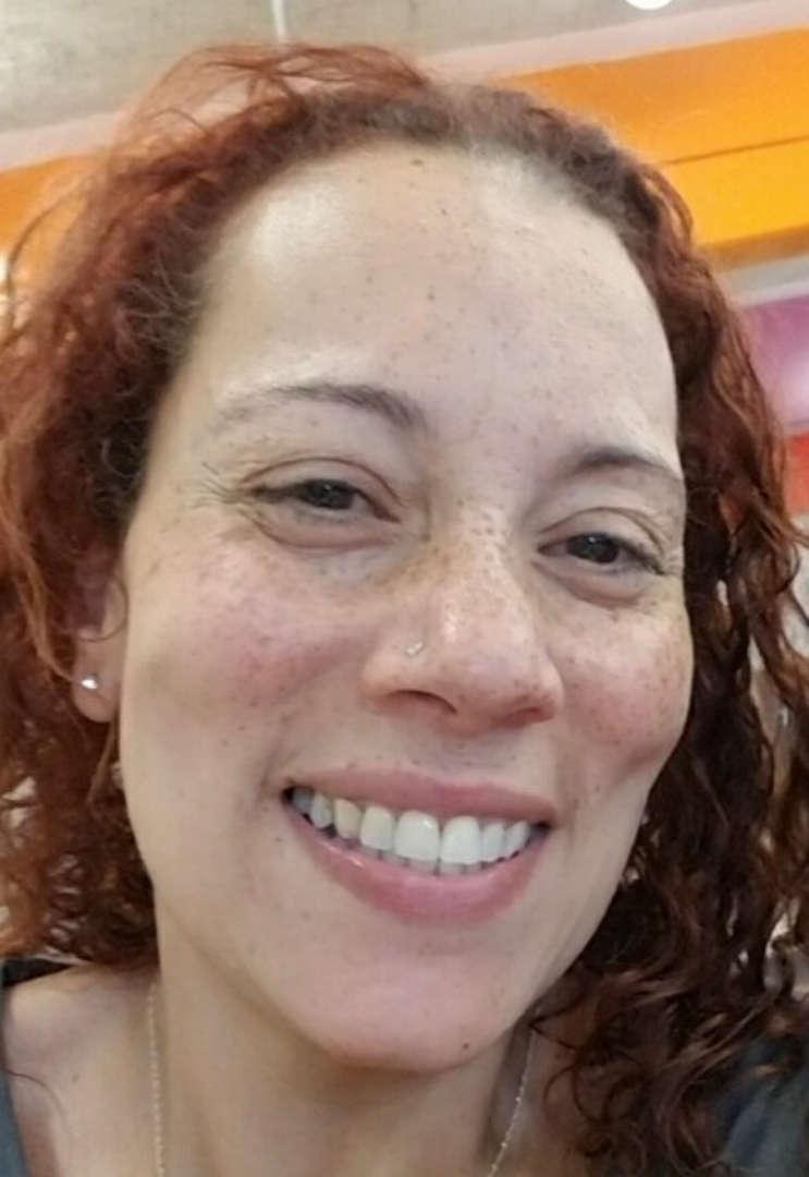 Close-up portrait of a woman with curly hair and a warm smile.