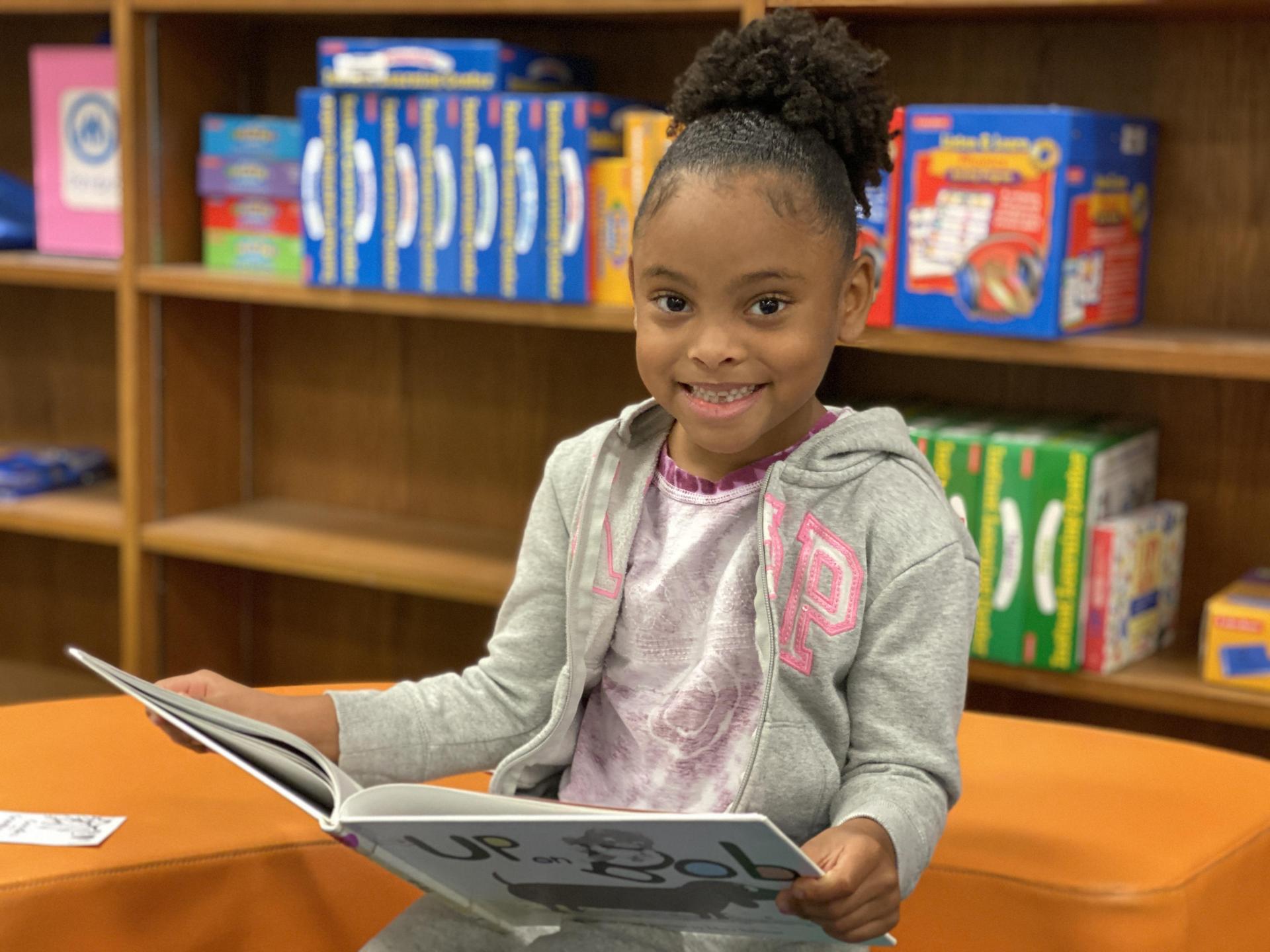 Smiling girl reading a book in a library