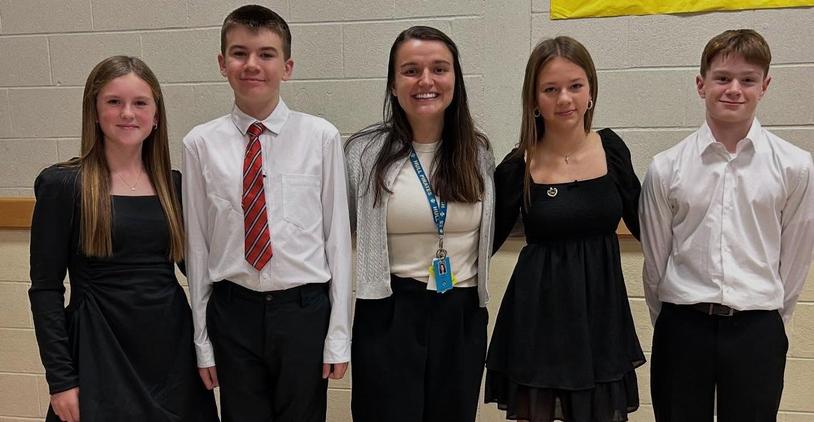 Five teenagers in formal attire posing together for a photo.