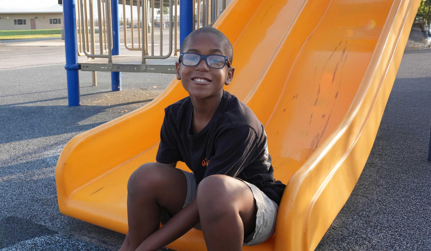 smiling boy sitting on slide
