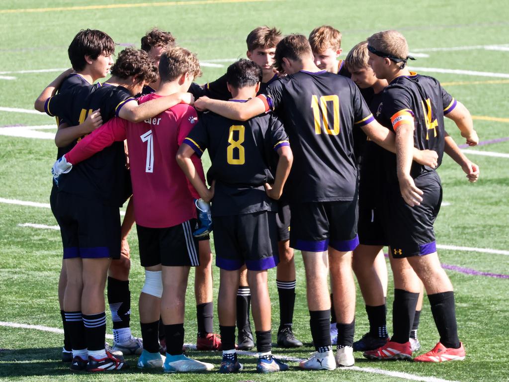 Soccer players in a huddle on the field.