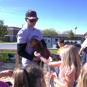 A student holds a young goat for elementary students to pet.